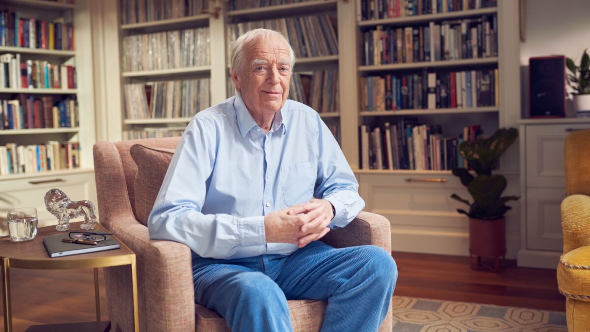 Sir Tim Rice poses for a photo sat in a chair